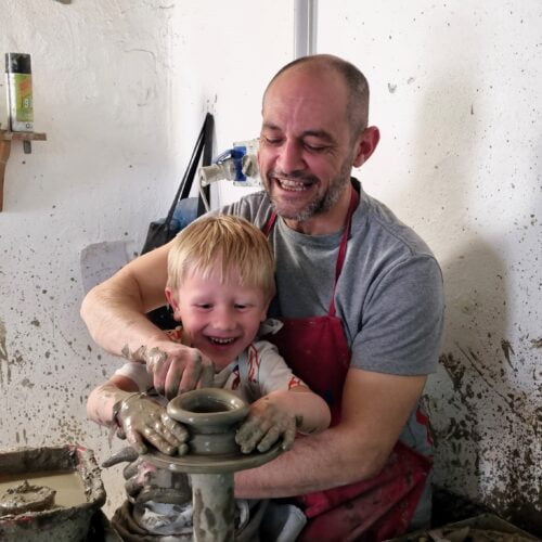 il maestro torniante insegna come modellare l'argilla al tornio a un bambino