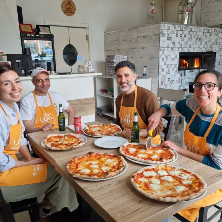 Happy participants at a Bari pizza making class enjoying fresh margherita after wood-fired bake during Loliv pizza experience