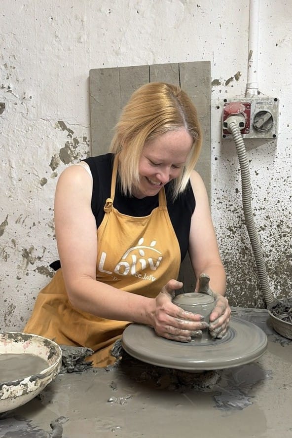 Traveller shaping clay on the pottery wheel during a traditional ceramic workshop, learning artisan techniques typical of Grottaglie