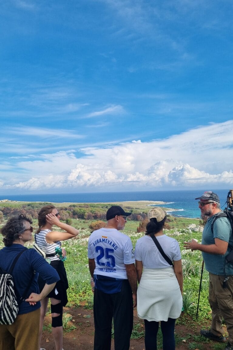 Travellers listening to their guide during a coastal hike, discovering the flora, history and panoramic sea views of Puglia