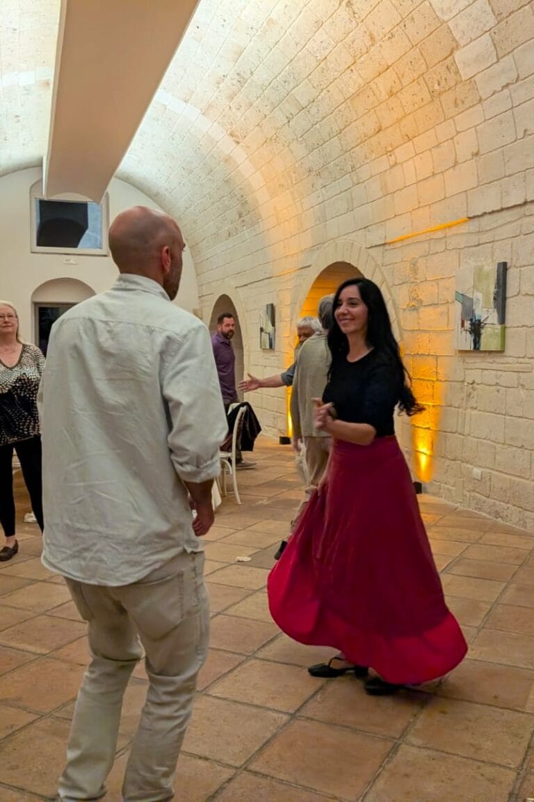 Guests learning the basic steps of pizzica with a local instructor, inside a historic hall that highlights Apulia’s folk dance traditions