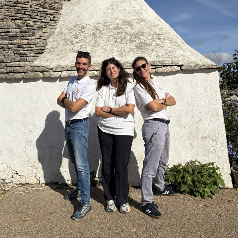 Loliv team with Claudia Romeo standing in front of a traditional trullo, united in crafting authentic travel experiences in Italy
