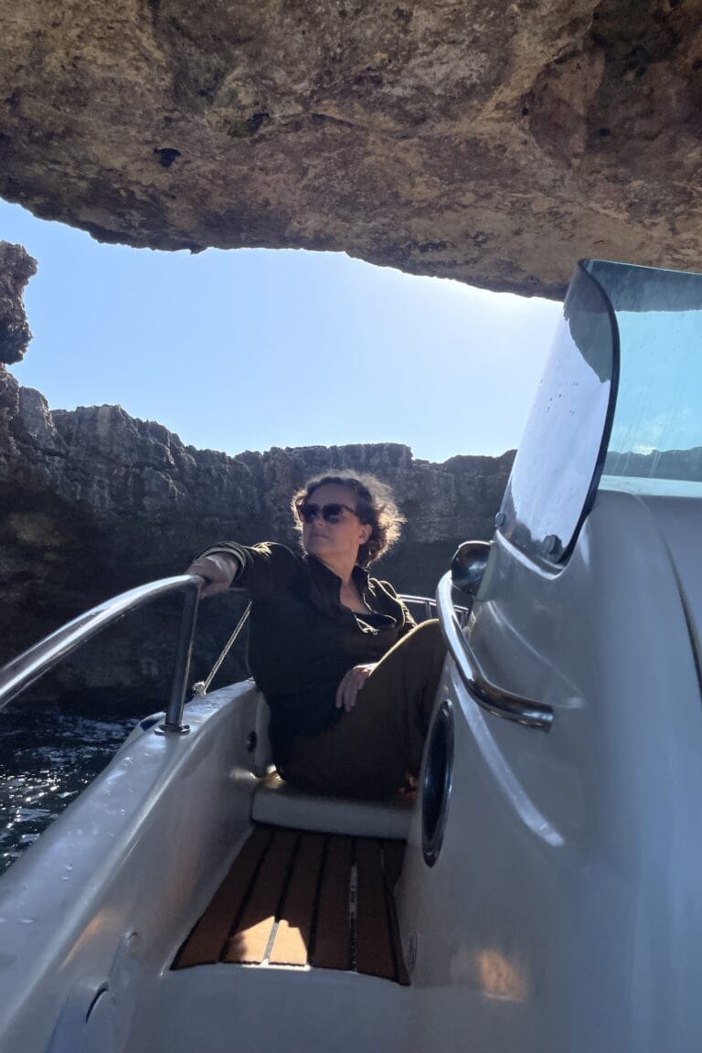 Viaggiatrice seduta in barca mentre attraversa una grotta marina a Polignano a Mare