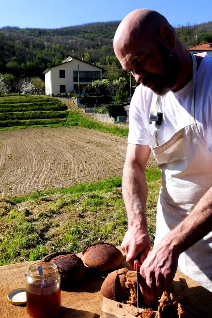 Artisan cutting a loaf of Marocca bread in a rural Tuscan setting