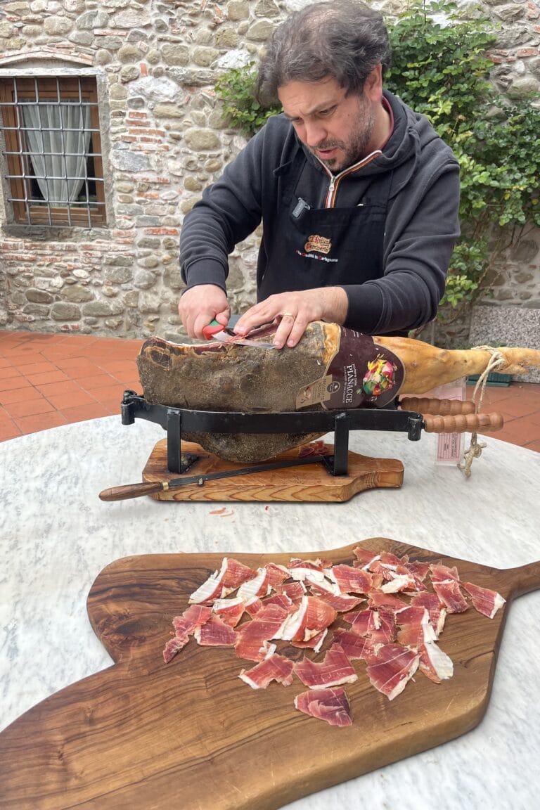 Local butcher slicing Bazzone prosciutto on a wooden board