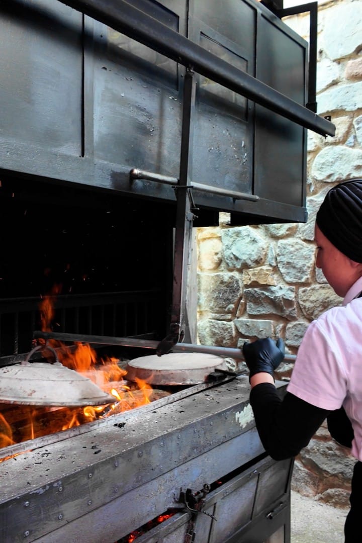 Artisan preparing testaroli on cast-iron plates over an open fire