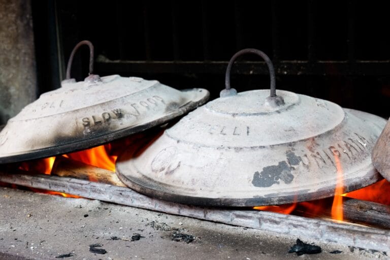 Traditional testaroli bread cooking on cast-iron plates over open fire