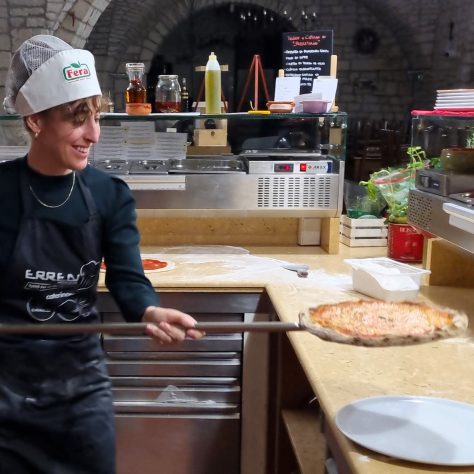 girl taking her pizza out of the oven during the pizza experience