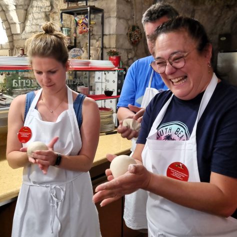 due signore imparano a fare le palline di massa per prepare la pizza