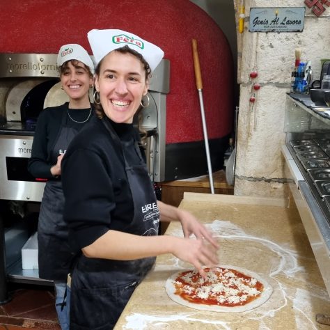 Smiling girls prepare their pizza during the pizza experience