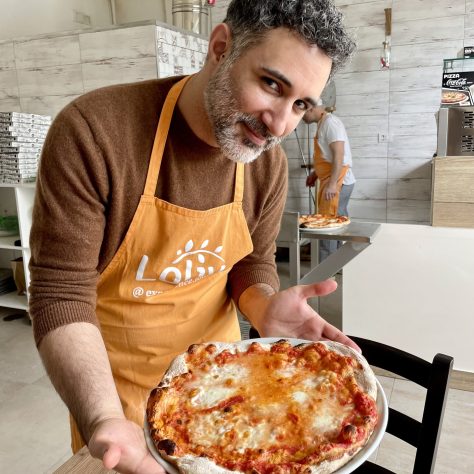 Participant presenting golden margherita baked in Bari pizza experience after 60-hour matured dough